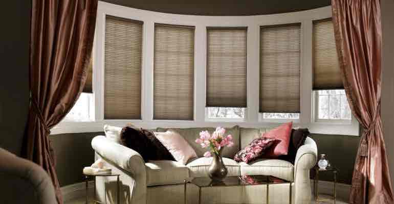 Adjustable cellular shades in living room bow window.